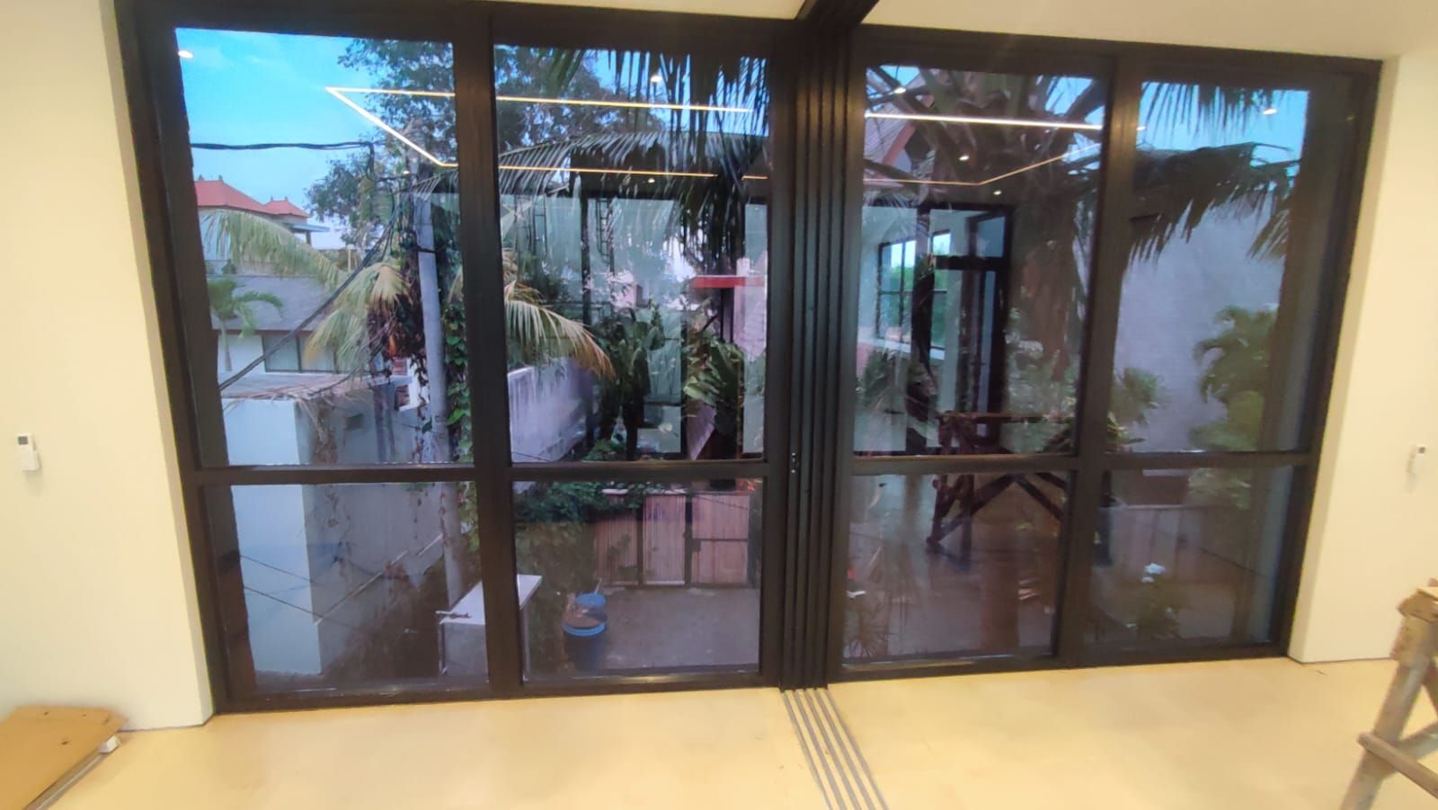 Folding glass villa di Bali dengan kaca film terpasang rapi menghadap taman tropis