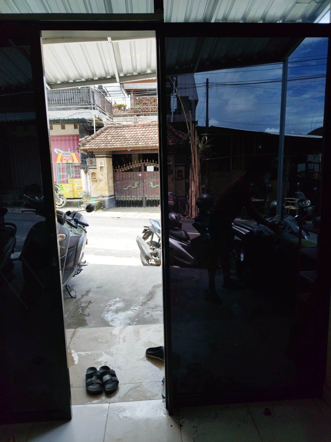 Panel pintu kaca sliding toko dengan film reflektif gelap, dilihat dari dalam ke arah jalan